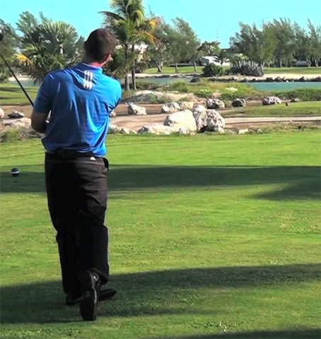 Man swings a club while playing golf