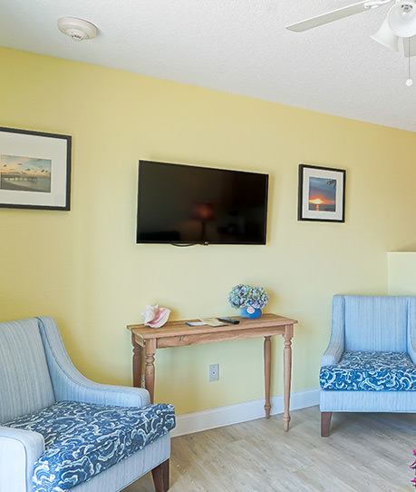 Flat screen tv mounted on wall with two chairs on each side